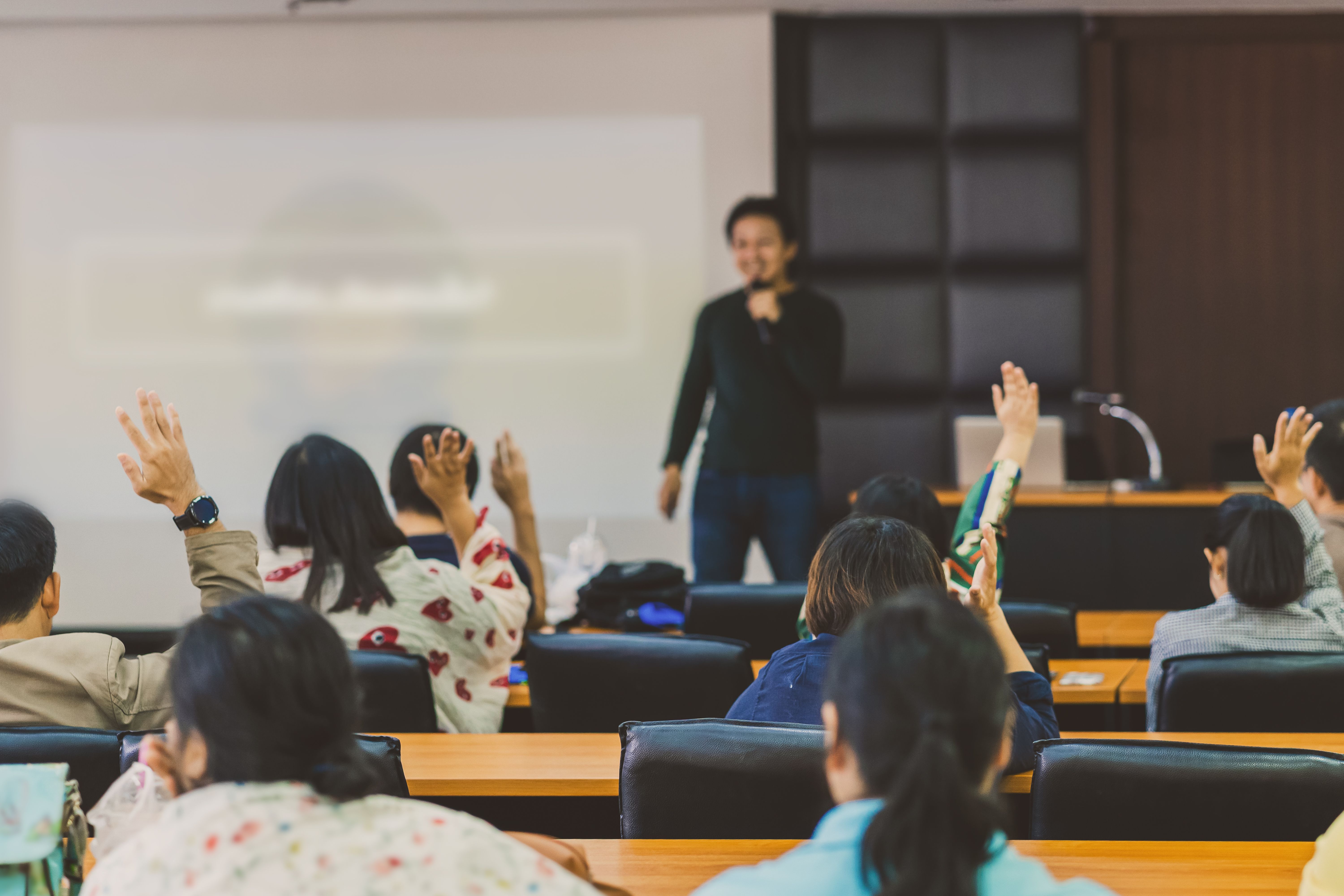 Presentation with audience members raising their hands